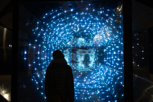 A person's silhouette against a bank of blue LEds.